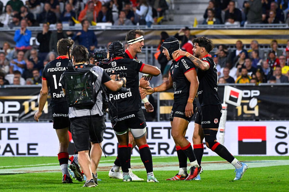 Match de rugby en cours dans un stade, avec deux équipes engagées en mêlée