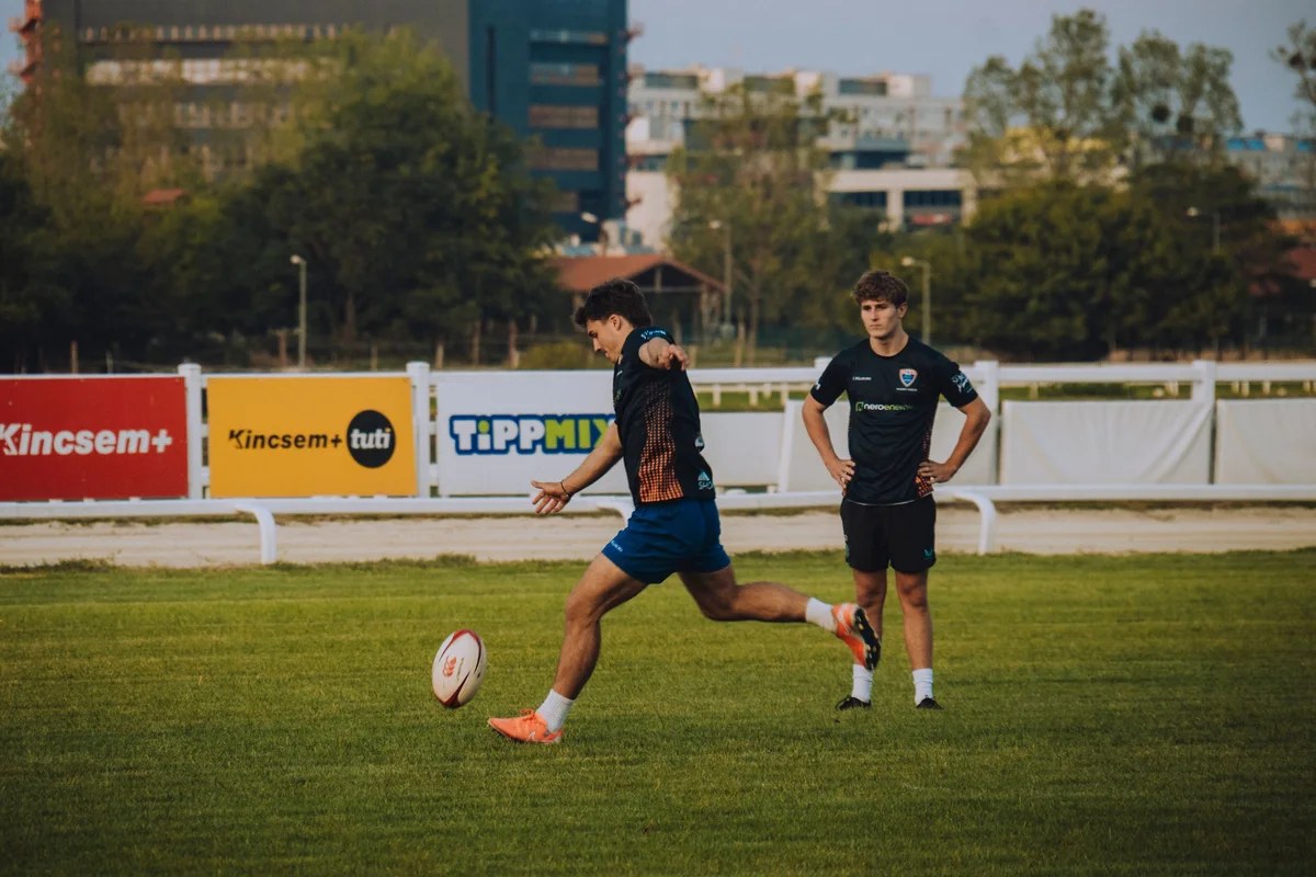 Enfants d'une école de rugby à l'entraînement avec un ballon ovale sur un terrain