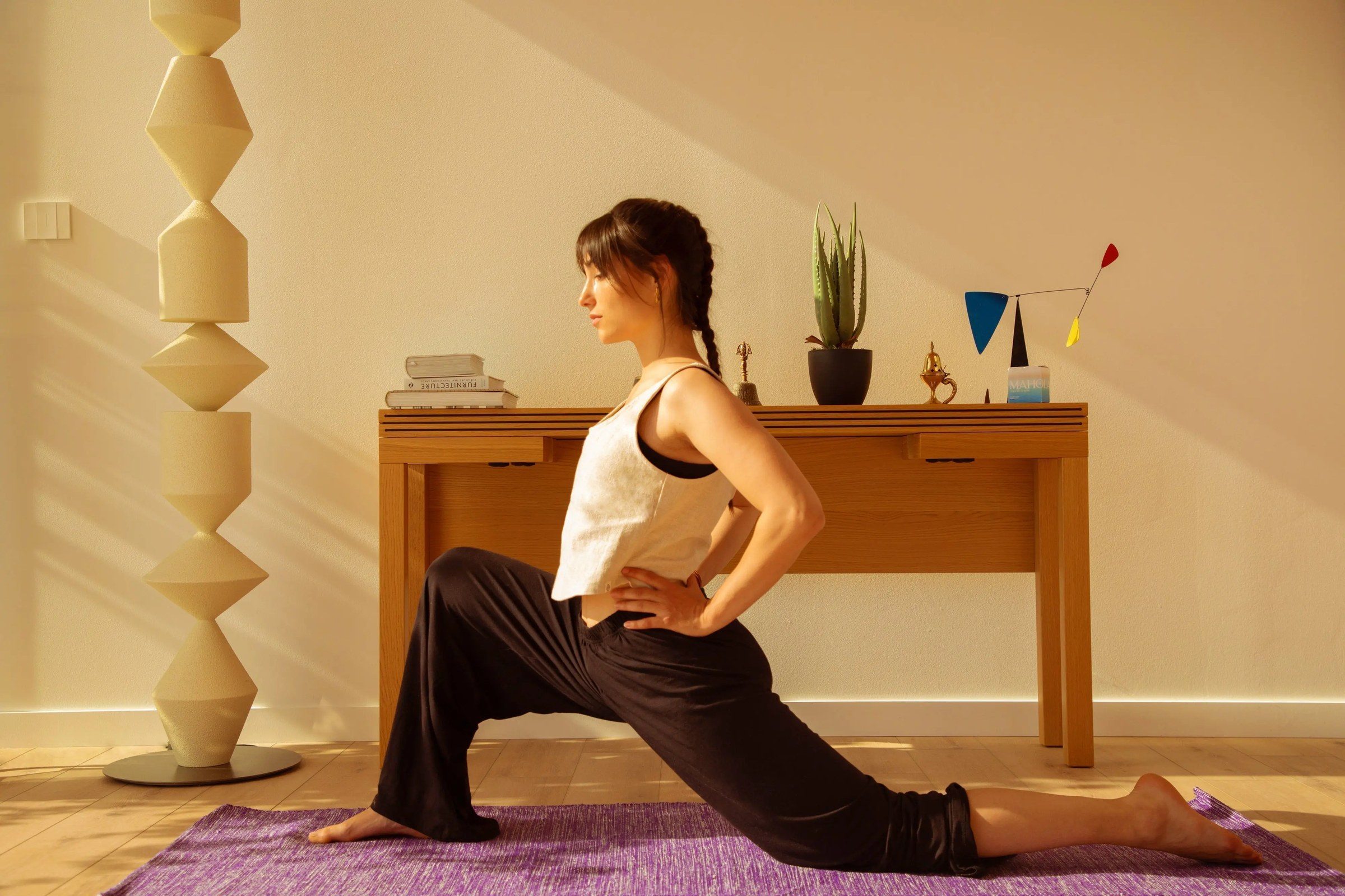 Pratiquante en salutation du soleil sur un tapis de yoga, bras levés au-dessus de la tête